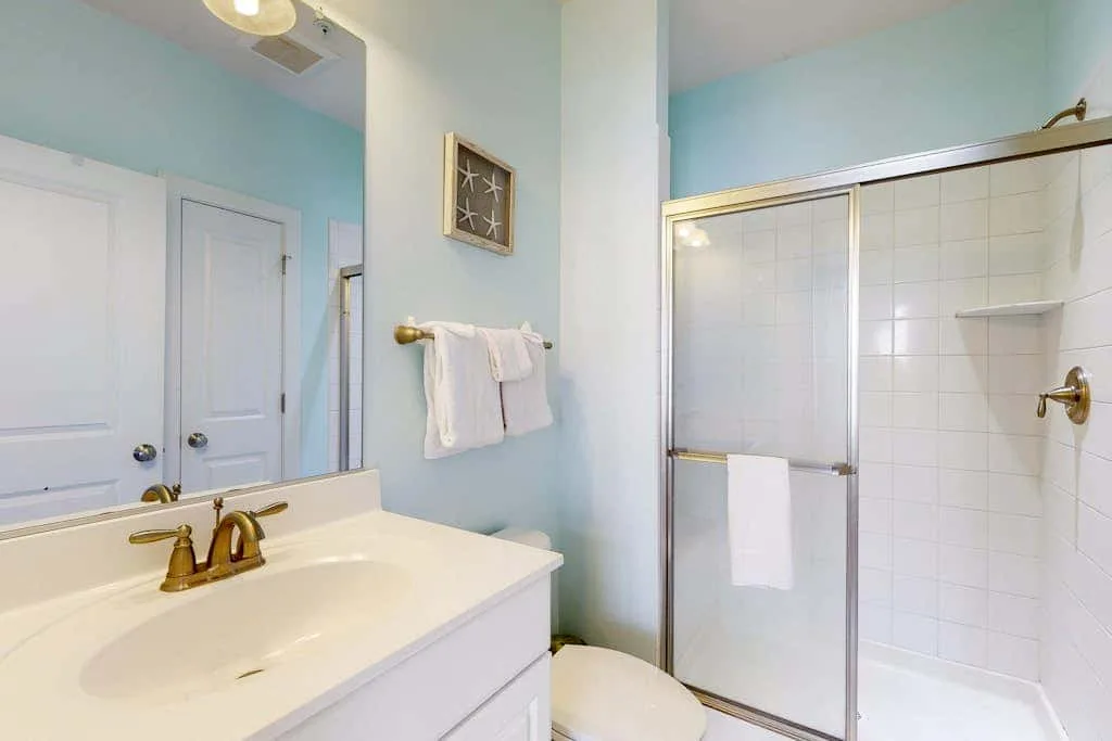 A bathroom with a sink, mirror, and glass shower.
