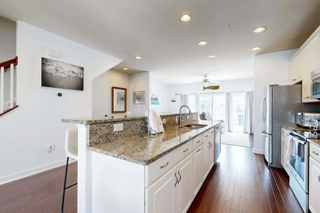 A bright kitchen with a long island and stainless steel appliances.