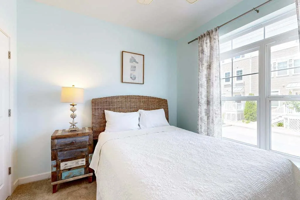 A bedroom with a bed beside a large window.