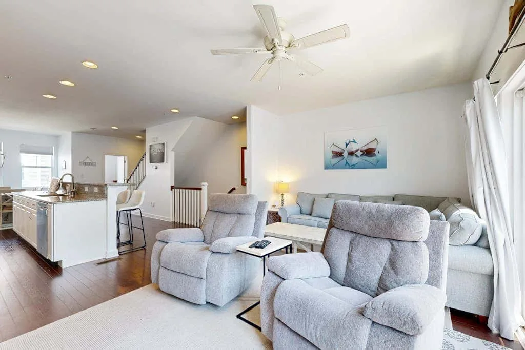 A bright living room with gray seating beside an open kitchen.