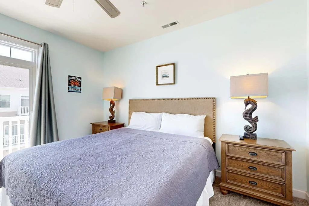 A bedroom with a neatly made bed between two bedside tables.