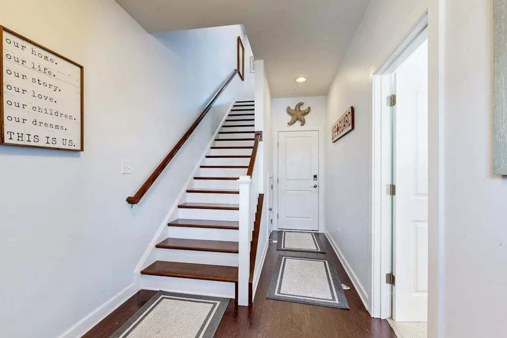 A bright entry hallway with a staircase and a front door.