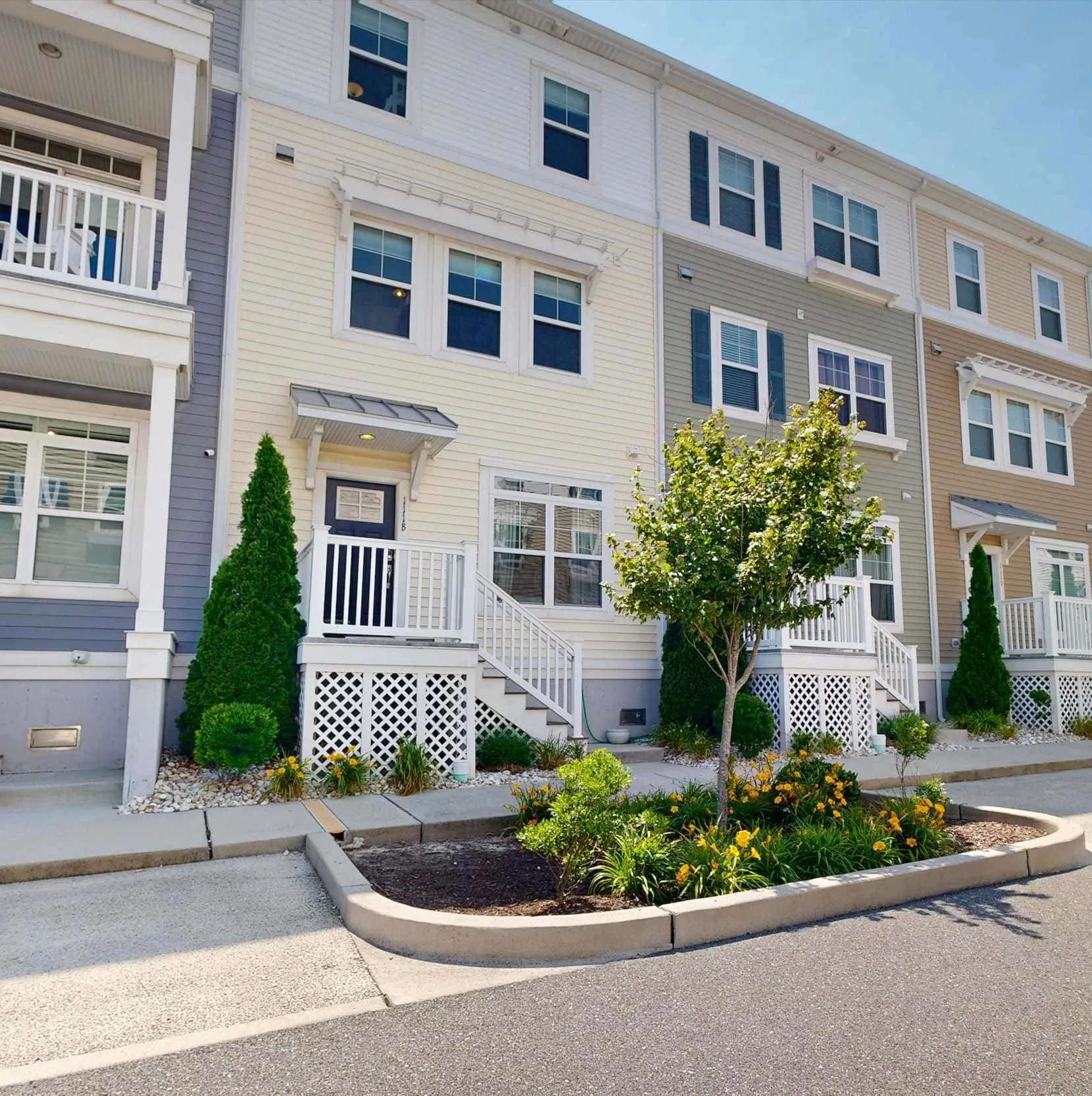 A row of attached homes with white balconies and landscaped planting beds.