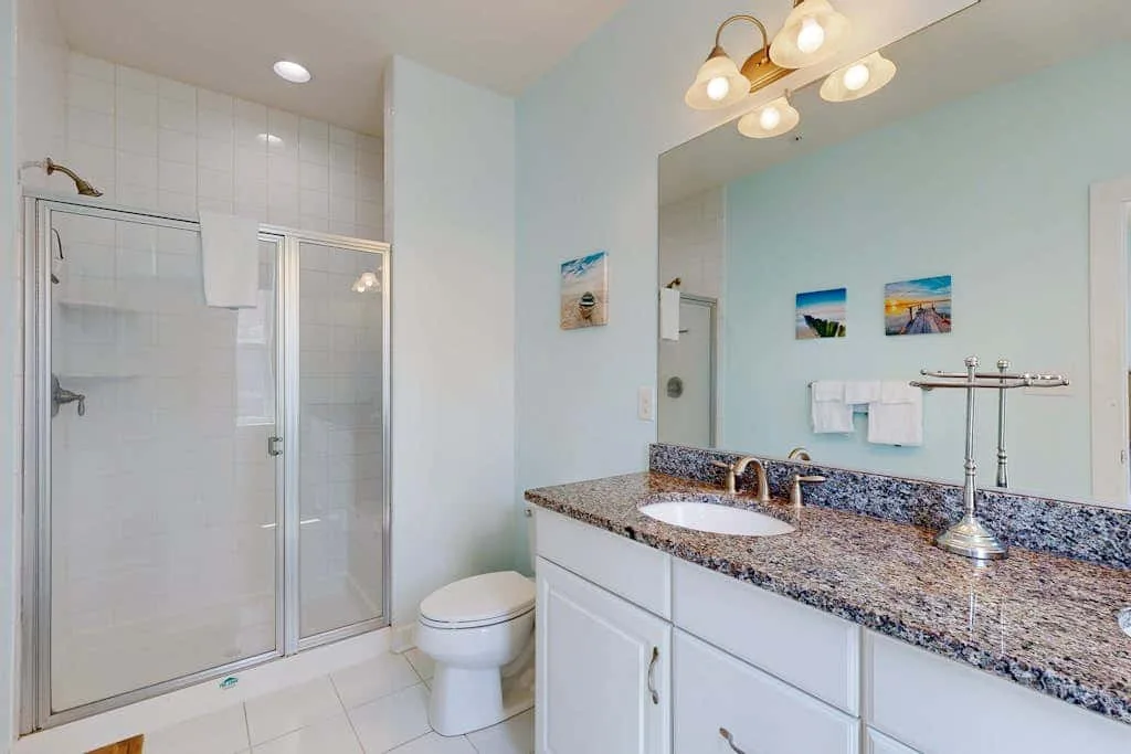 A bright bathroom with a glass shower and a long vanity.