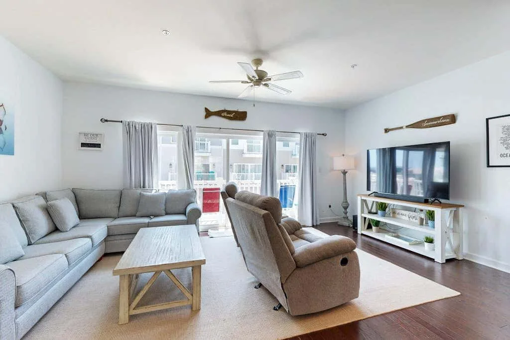 A bright living room with seating, a coffee table, and a television.