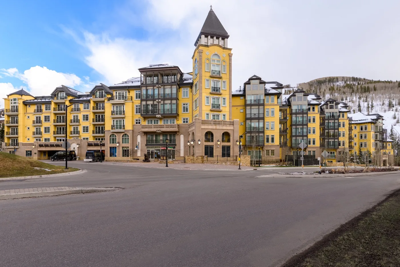 A large yellow building with a tower stands beside a paved road.