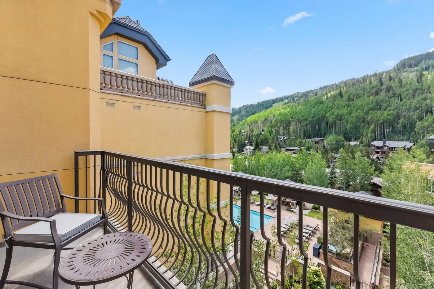 A balcony overlooks a wooded hillside and buildings below.