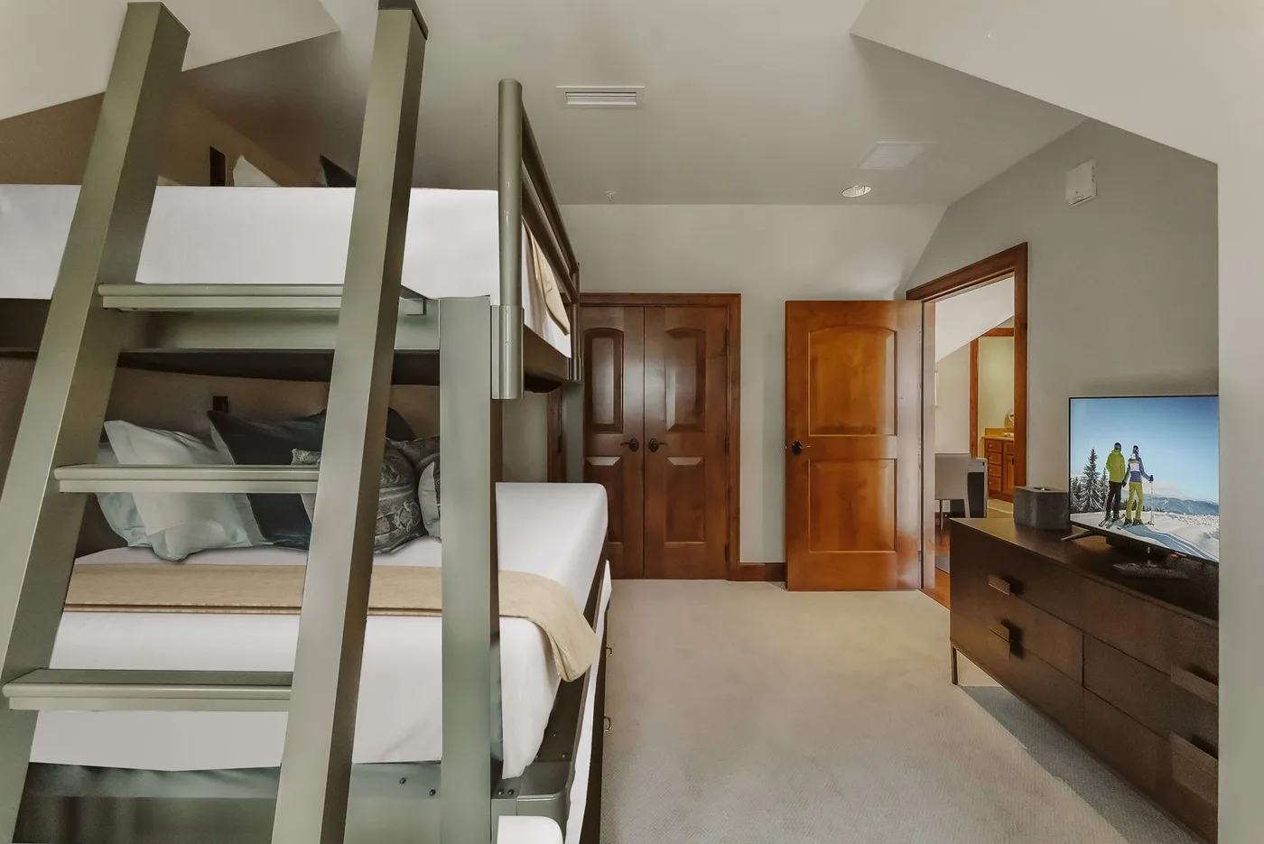 A bedroom with bunk beds, wooden doors, and a television on a dresser.