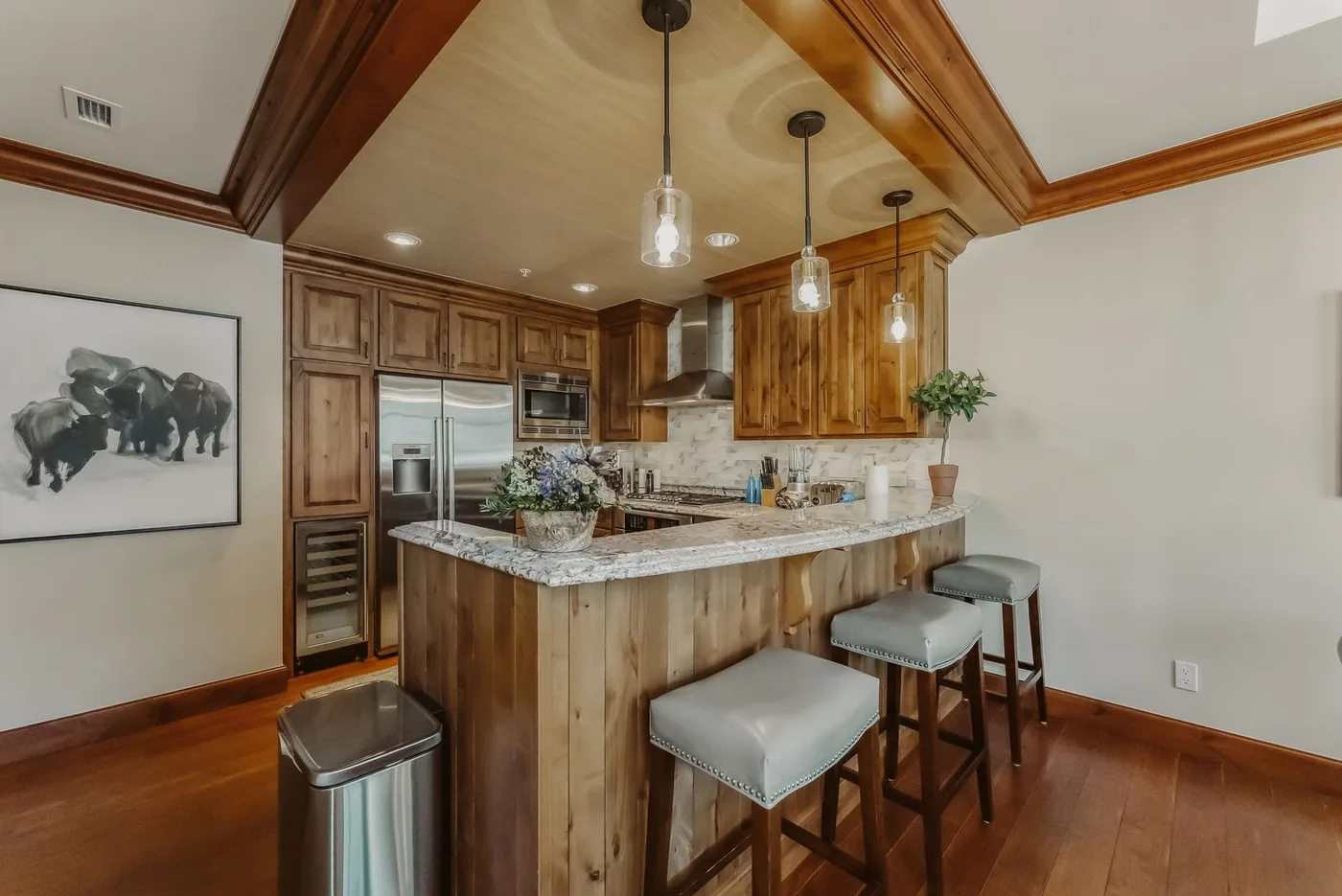 A kitchen with a wood-fronted island and stools.