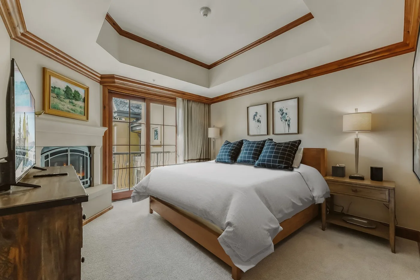 A bedroom with a large bed, bedside tables, and a fireplace.