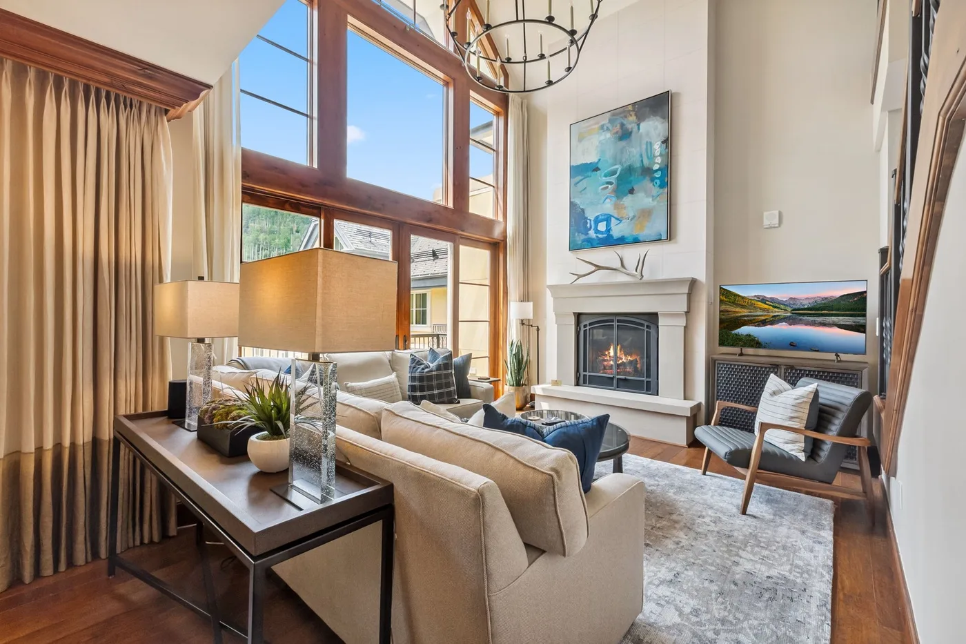 A bright living room with tall windows, seating, and a fireplace.