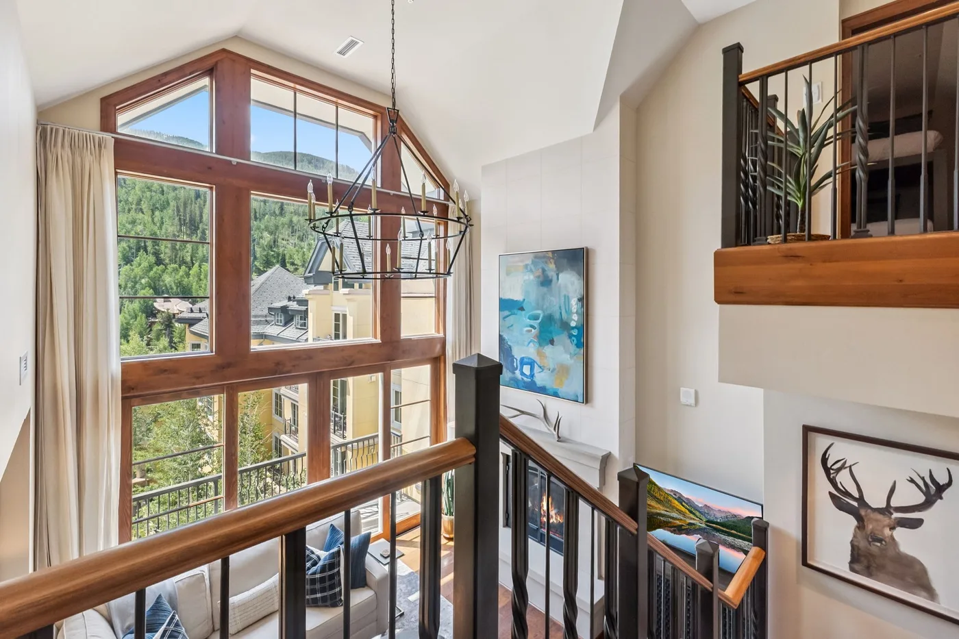 A bright, open living area overlooks large windows and a wooden balcony railing.
