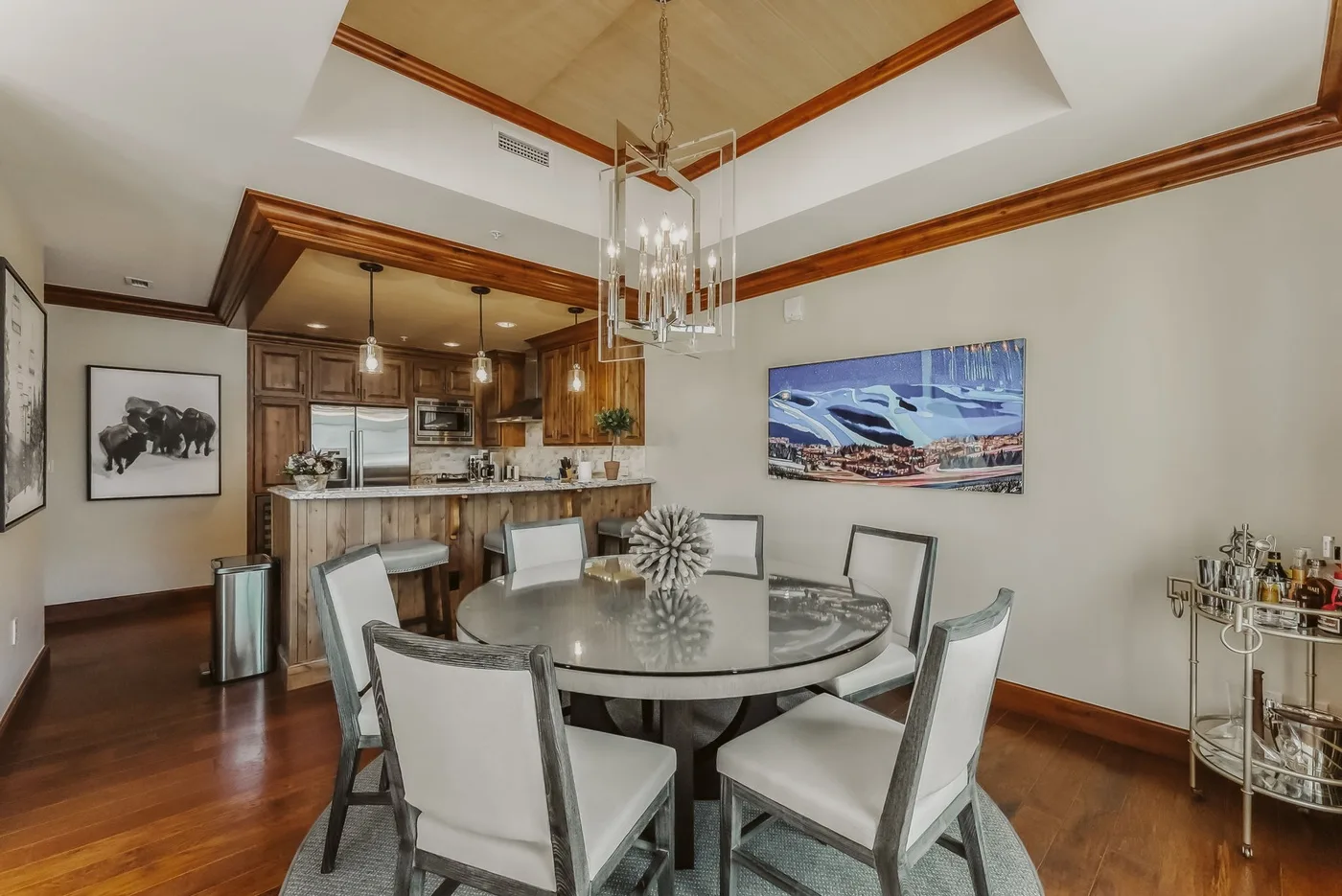 A dining area with a round table and seating beside an open kitchen.