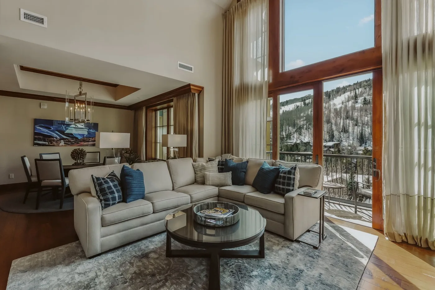A bright living room with seating beside tall windows overlooking a mountain view.