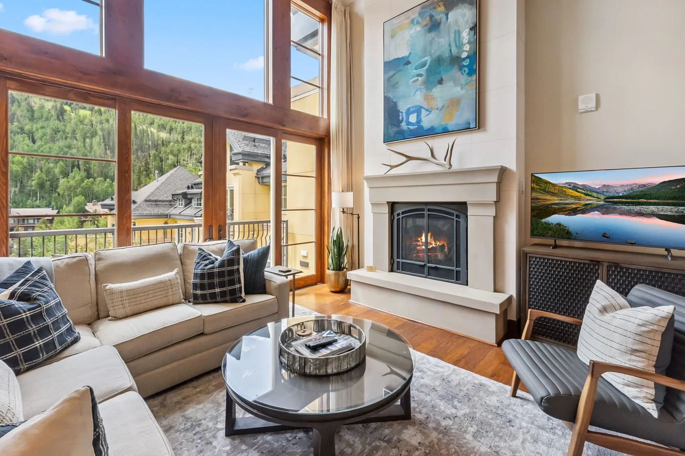 A living room with large windows, seating, and a fireplace.