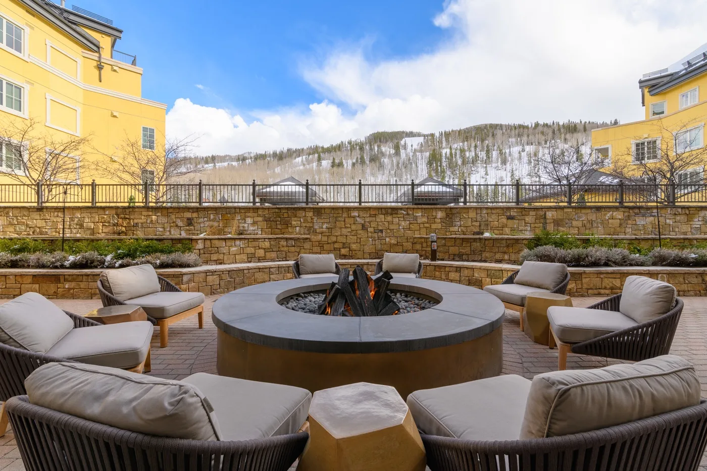 An outdoor patio with cushioned seating arranged around a circular fire pit.