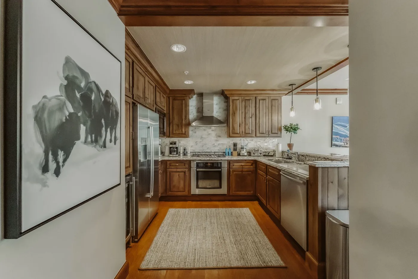 A kitchen with wooden cabinets, stainless-steel appliances, and a central work area.