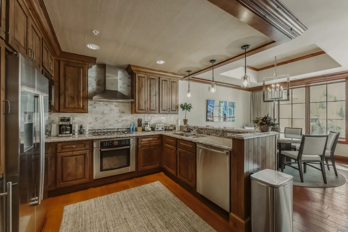 A spacious kitchen with wood cabinetry, stainless appliances, and a dining area.