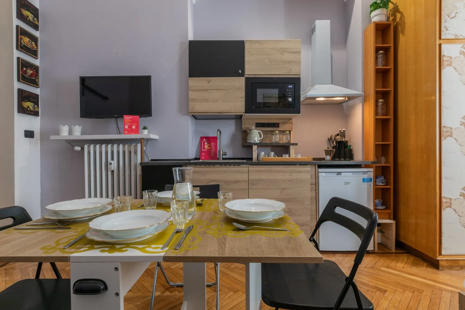 Un comedor con la mesa puesta frente a una cocina compacta.