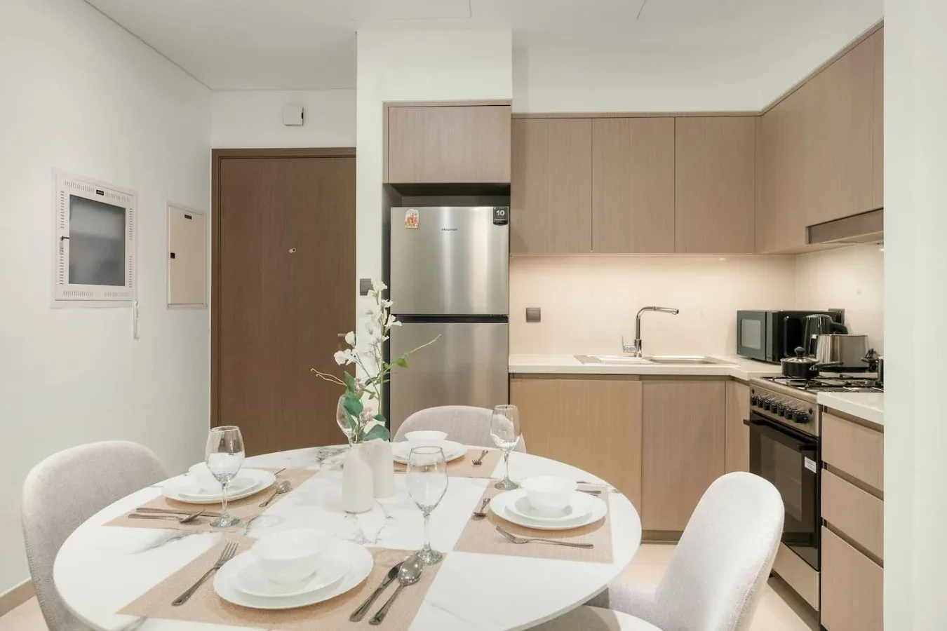 Una mesa con vajilla está junto a una cocina compacta.
