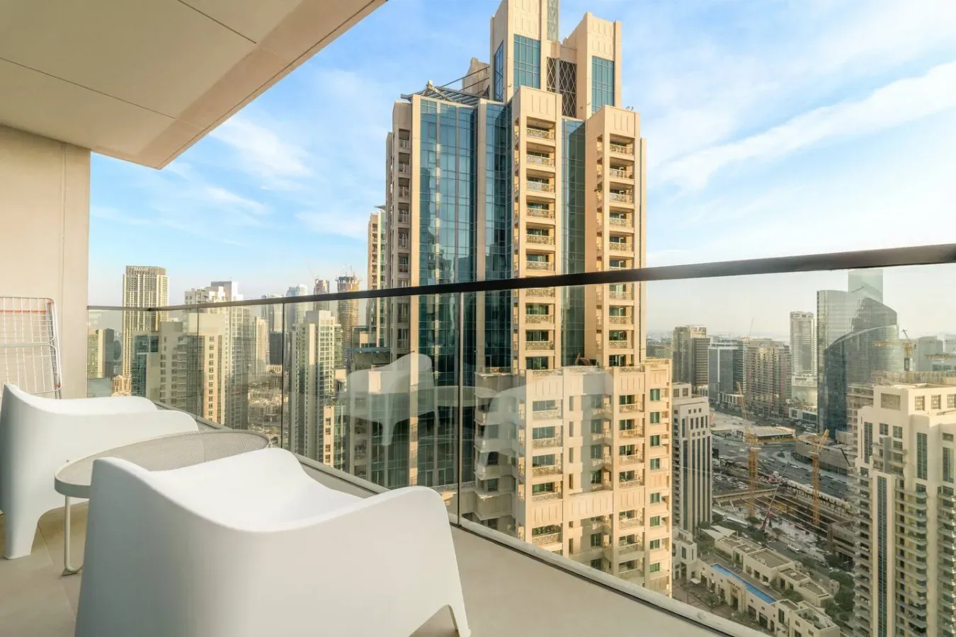 A balcony with white seating overlooks a cluster of city high-rises.