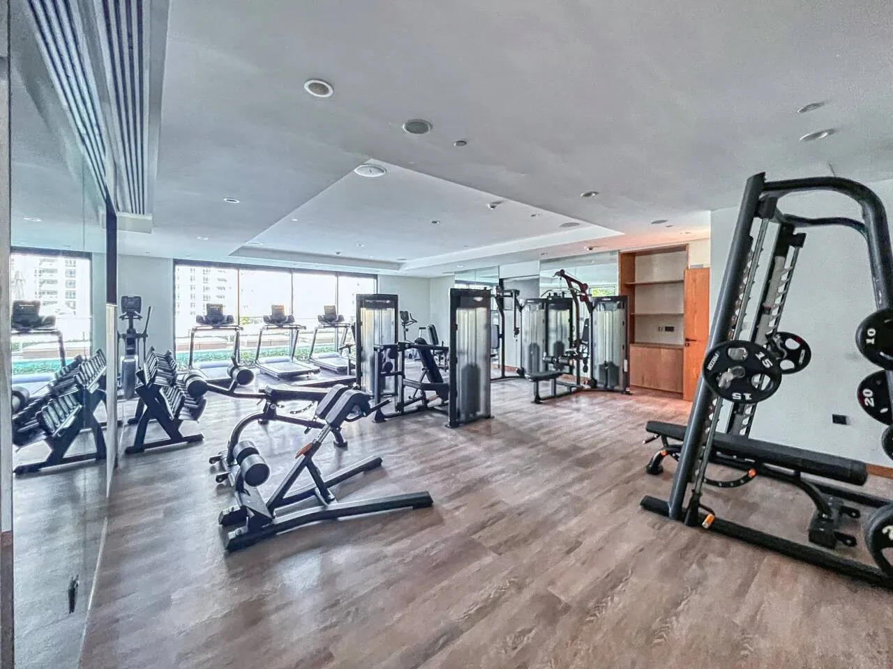 Un gimnasio interior luminoso con máquinas de ejercicio y grandes ventanas.