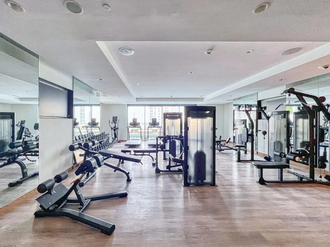 Un gimnasio luminoso con máquinas de ejercicio y pesas distribuidas por la sala.