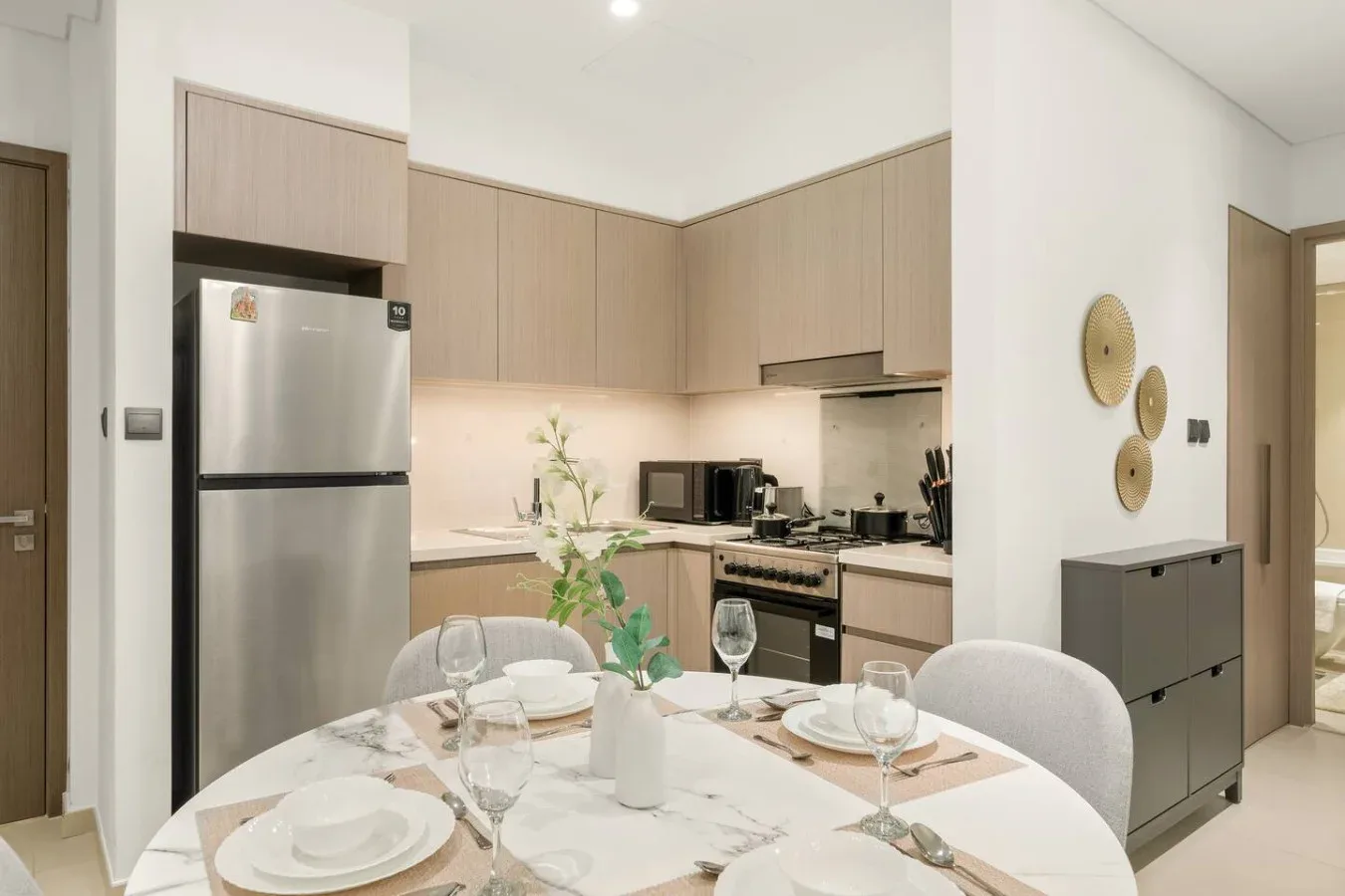 Una mesa de comedor con puestos preparados está frente a una cocina compacta.