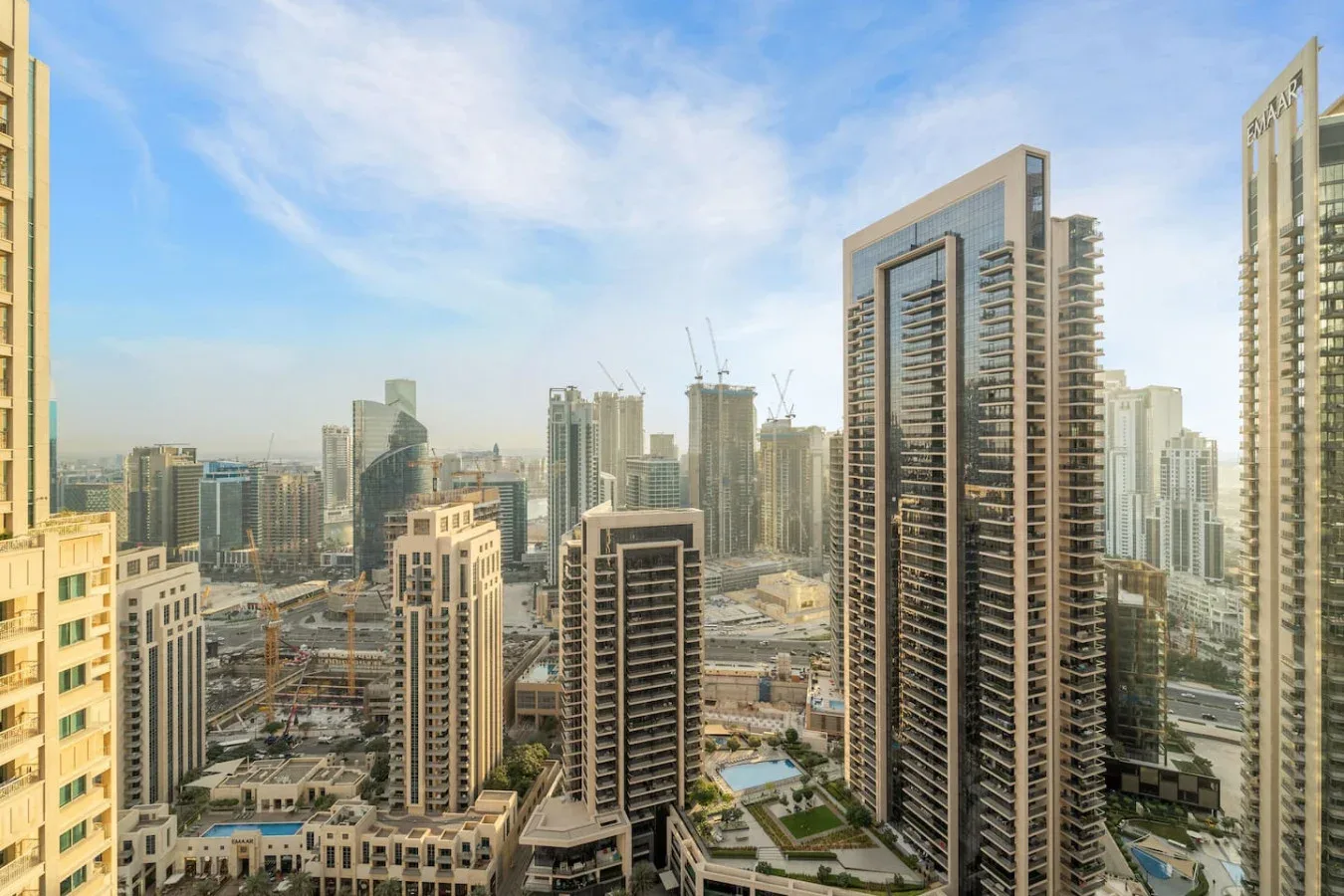 Un horizonte urbano con edificios altos y obras en construcción bajo un cielo azul.