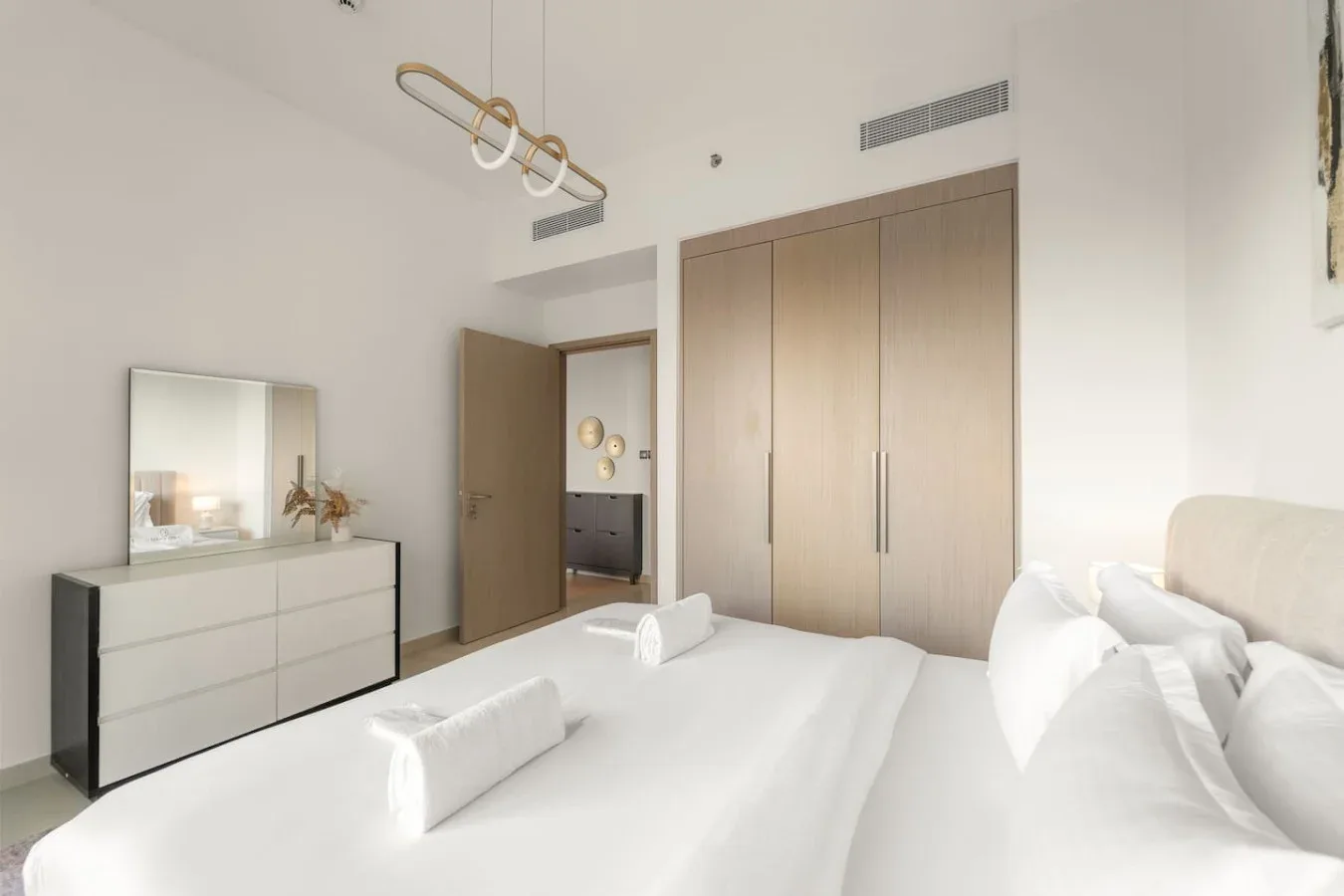 Un dormitorio luminoso con una cama bien tendida y un armario empotrado.