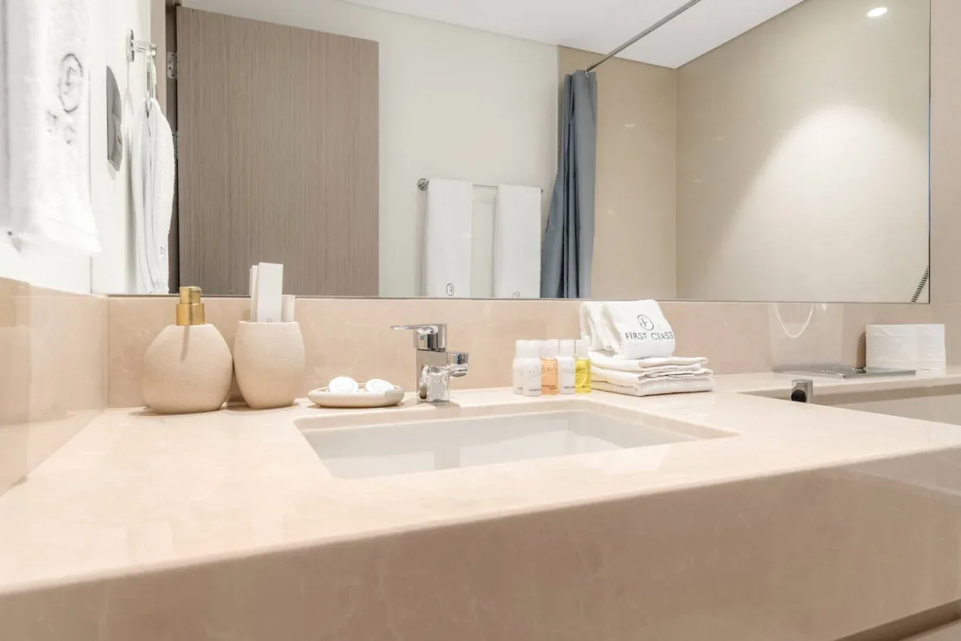 Un lavabo de baño con una amplia pila, artículos de aseo y toallas dobladas.