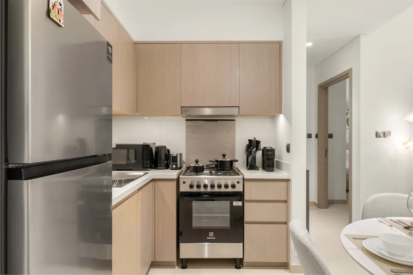 Una cocina moderna con gabinetes de madera clara, un refrigerador y una estufa.