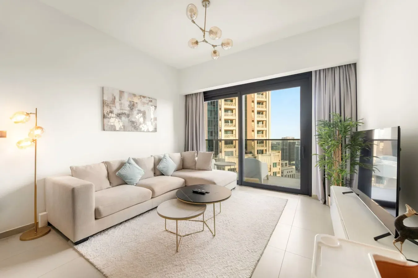 A bright living room with a sectional seating area and large glass doors opening to a balcony.