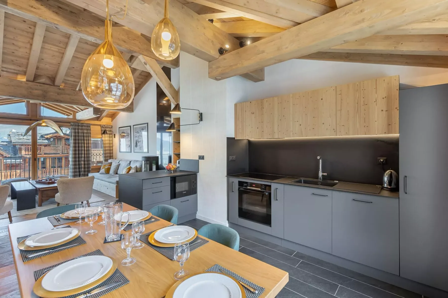An open-plan kitchen and dining area with a wooden table and exposed ceiling beams.