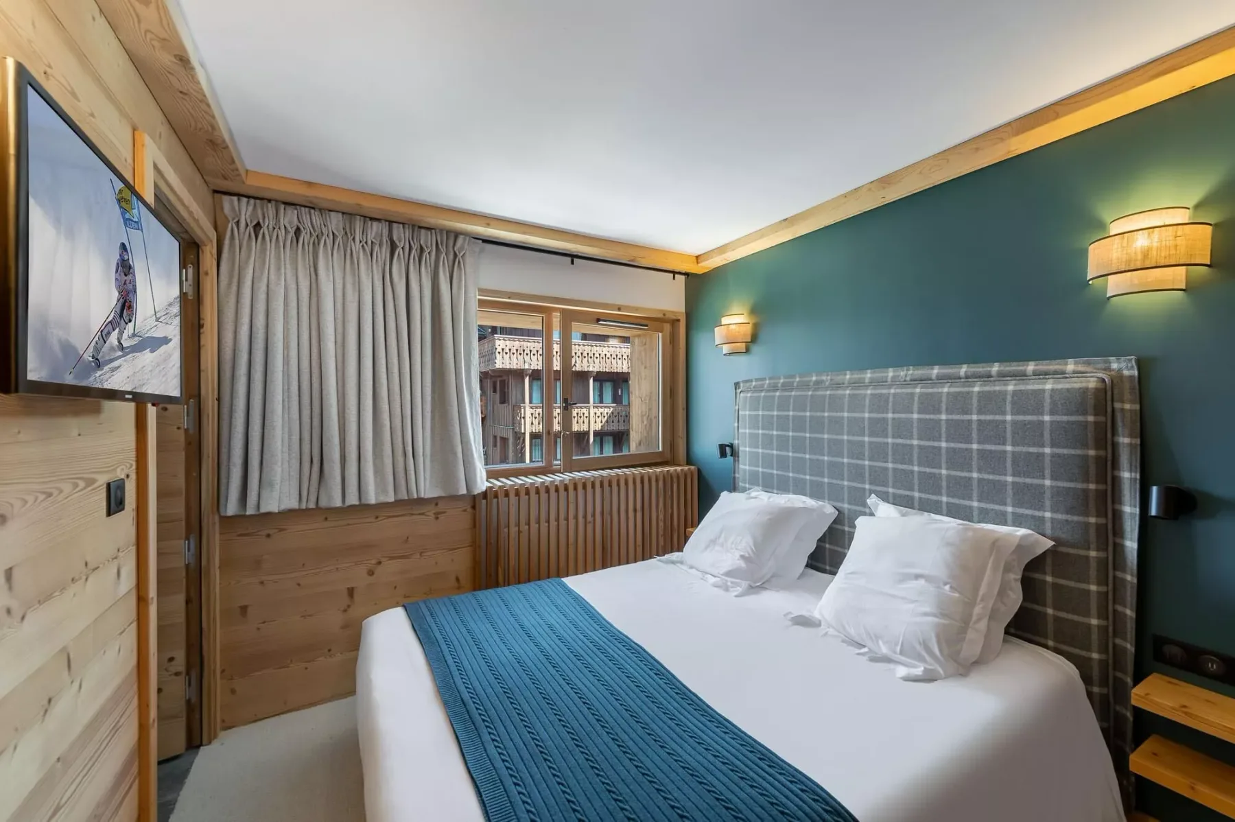 A bedroom with a neatly made bed and a teal accent wall.