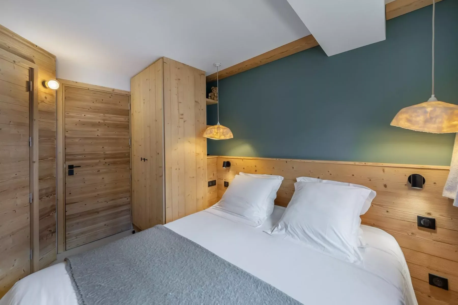 A bedroom with a double bed, white bedding, and wood-paneled walls.