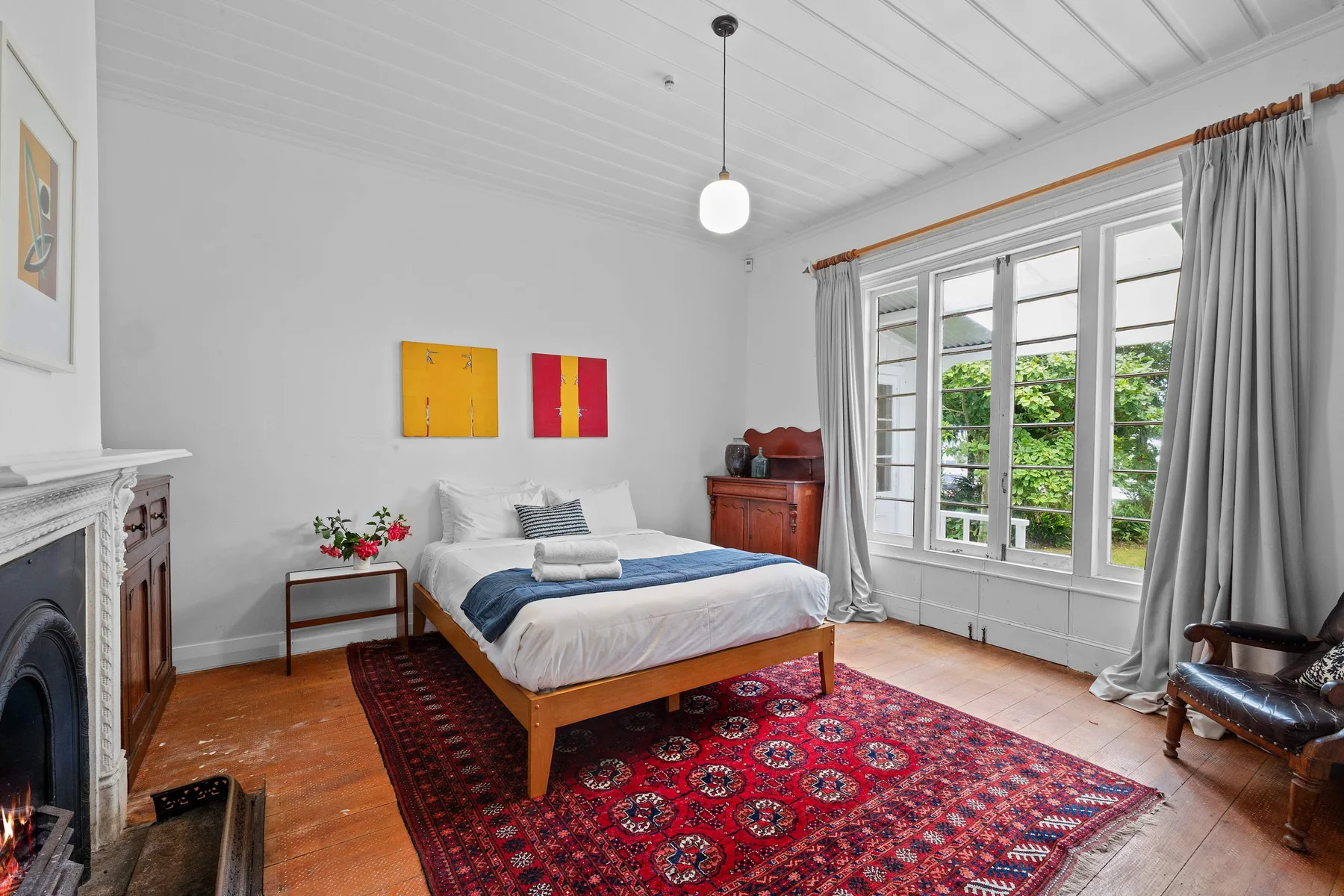 Un dormitorio con una cama junto a grandes ventanas y una alfombra estampada.