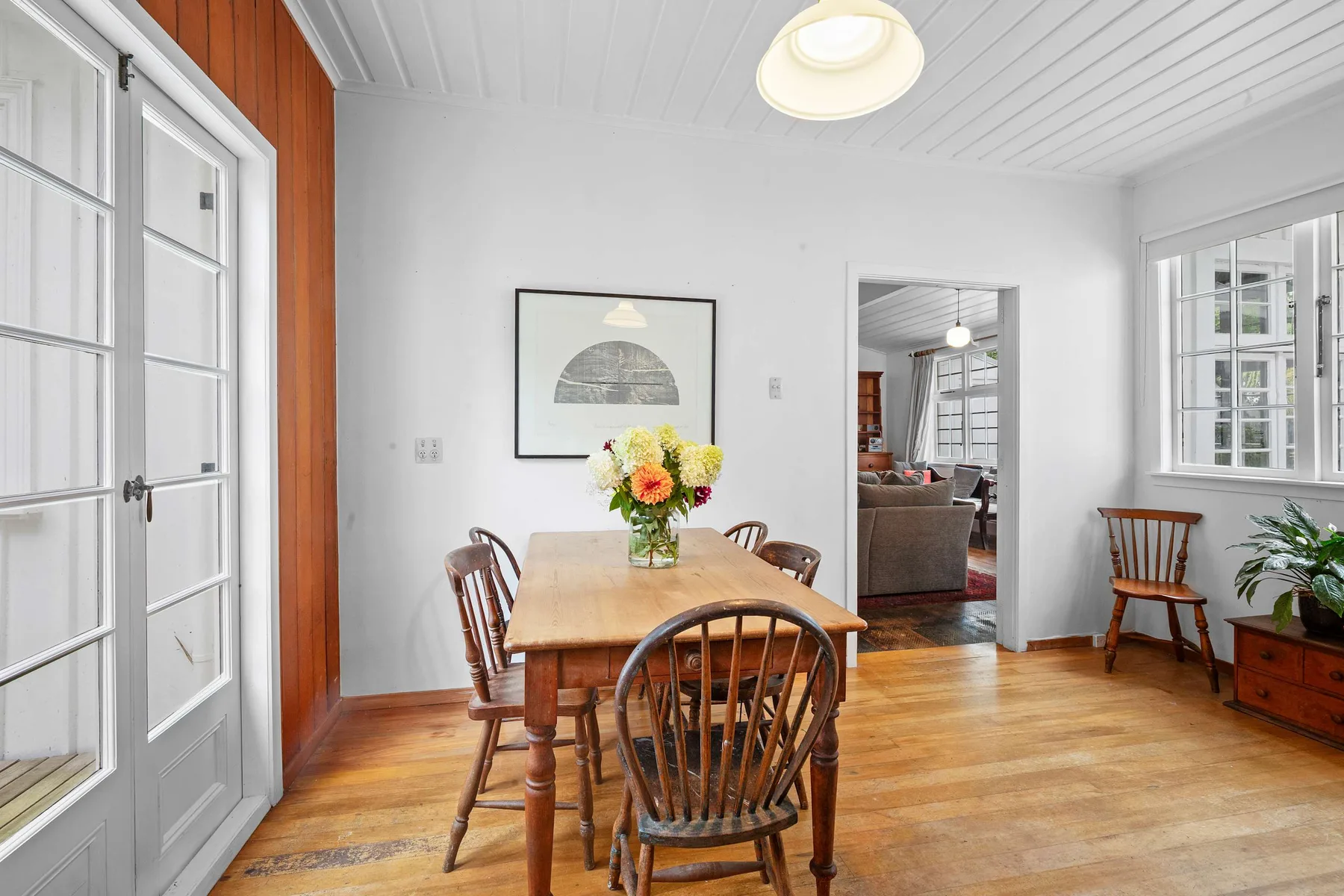Un comedor luminoso con una mesa y sillas de madera junto a una puerta que da a la sala.