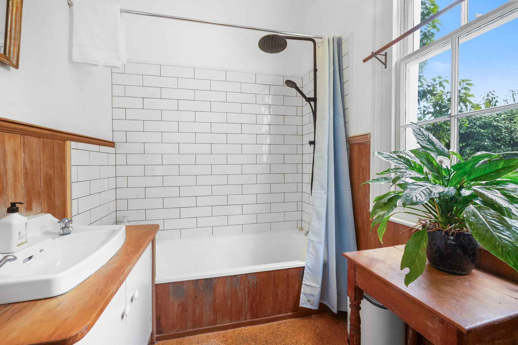 Un baño luminoso con una ducha de azulejos y una ventana grande.