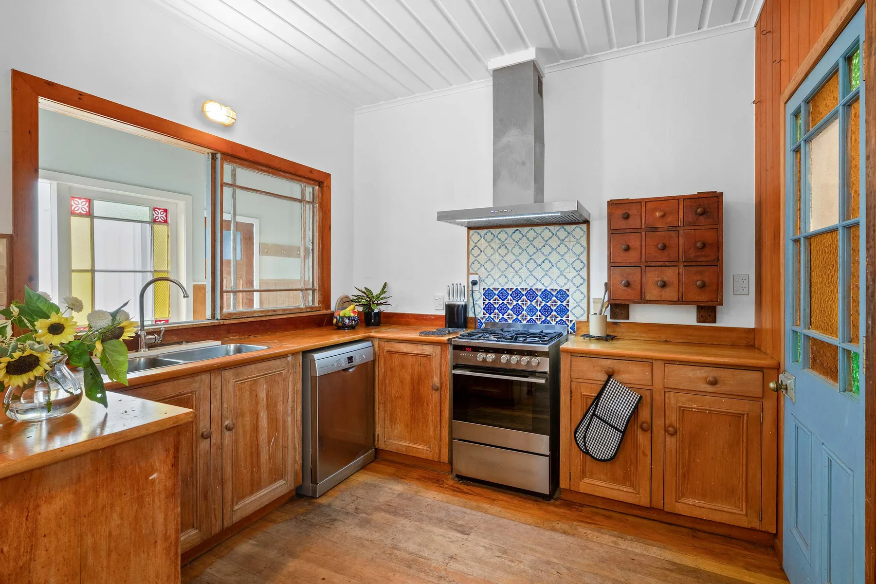 Una cocina de tonos cálidos con gabinetes de madera, una estufa y un salpicadero de azulejos azules.
