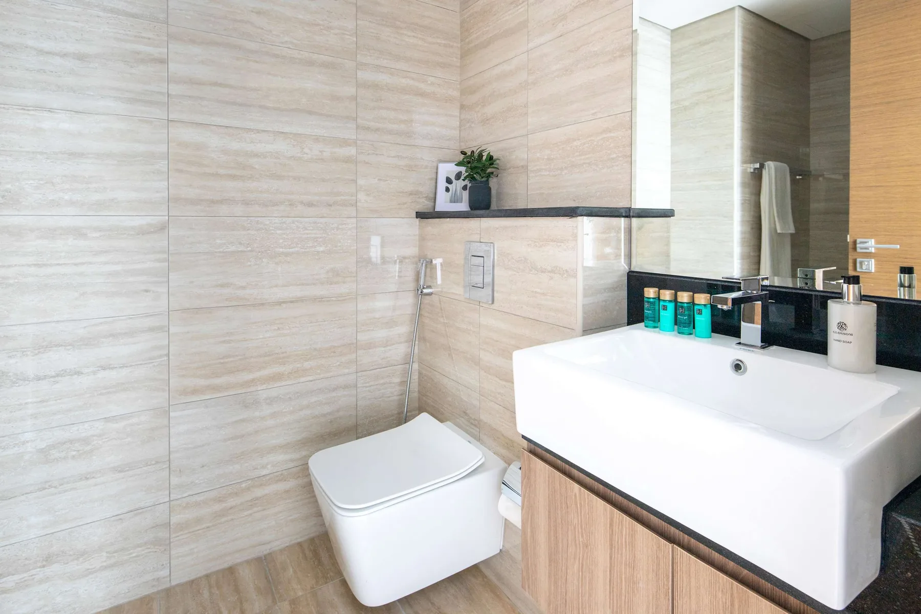 A modern bathroom with a wall-mounted toilet and a wide sink.