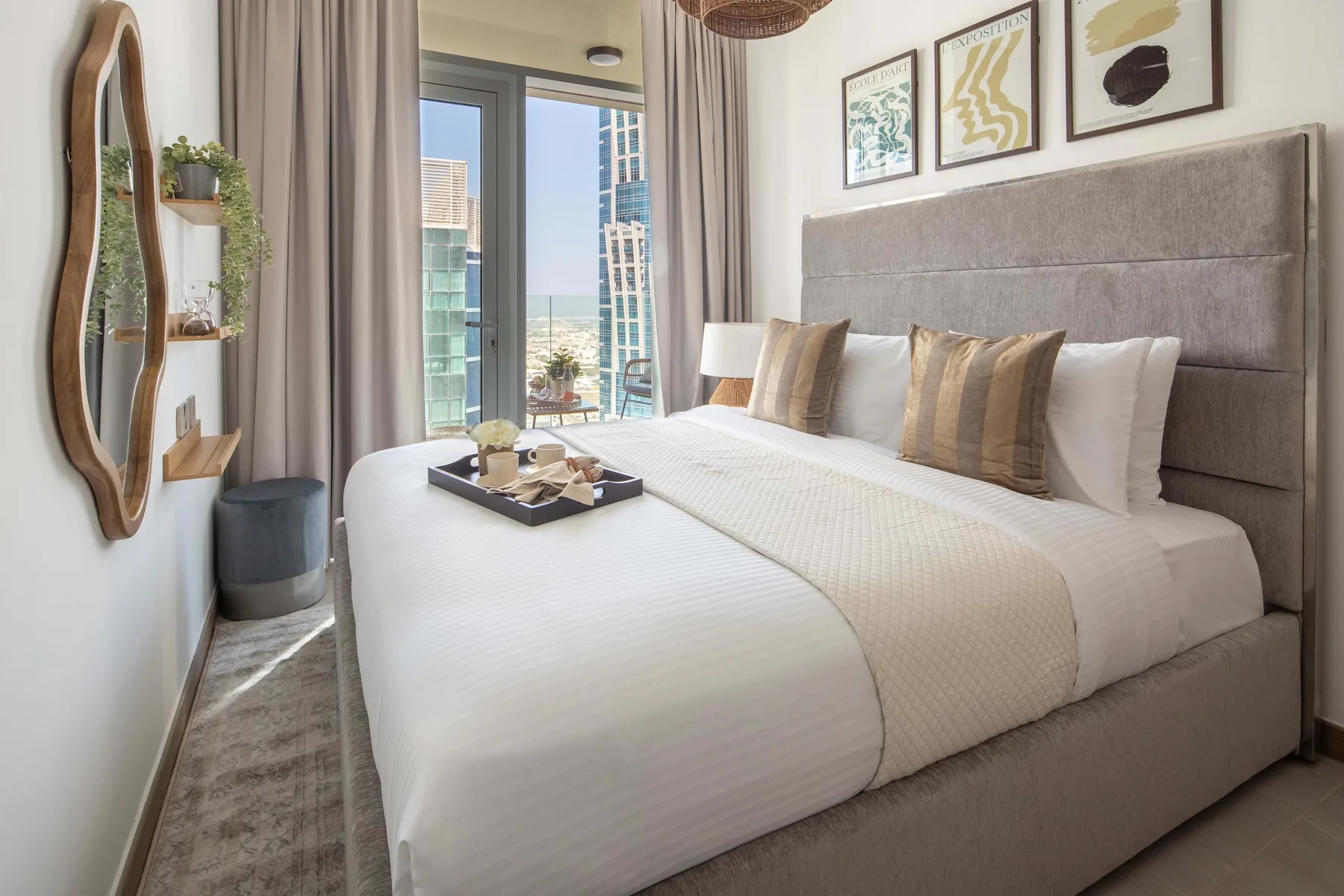 A bright bedroom with a neatly made bed and large windows.