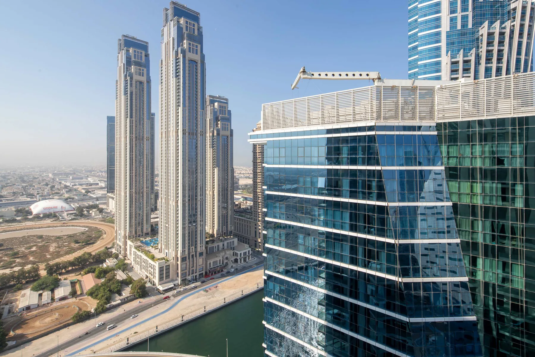 A city skyline with tall towers beside a glass office building and a waterway.