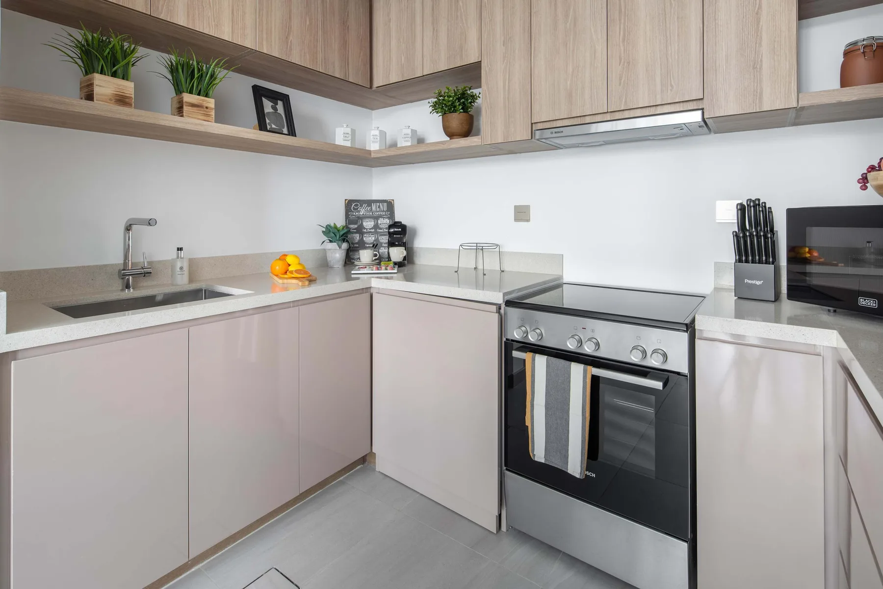 A modern kitchen with pale cabinetry, a sink, and a stainless-steel stove.