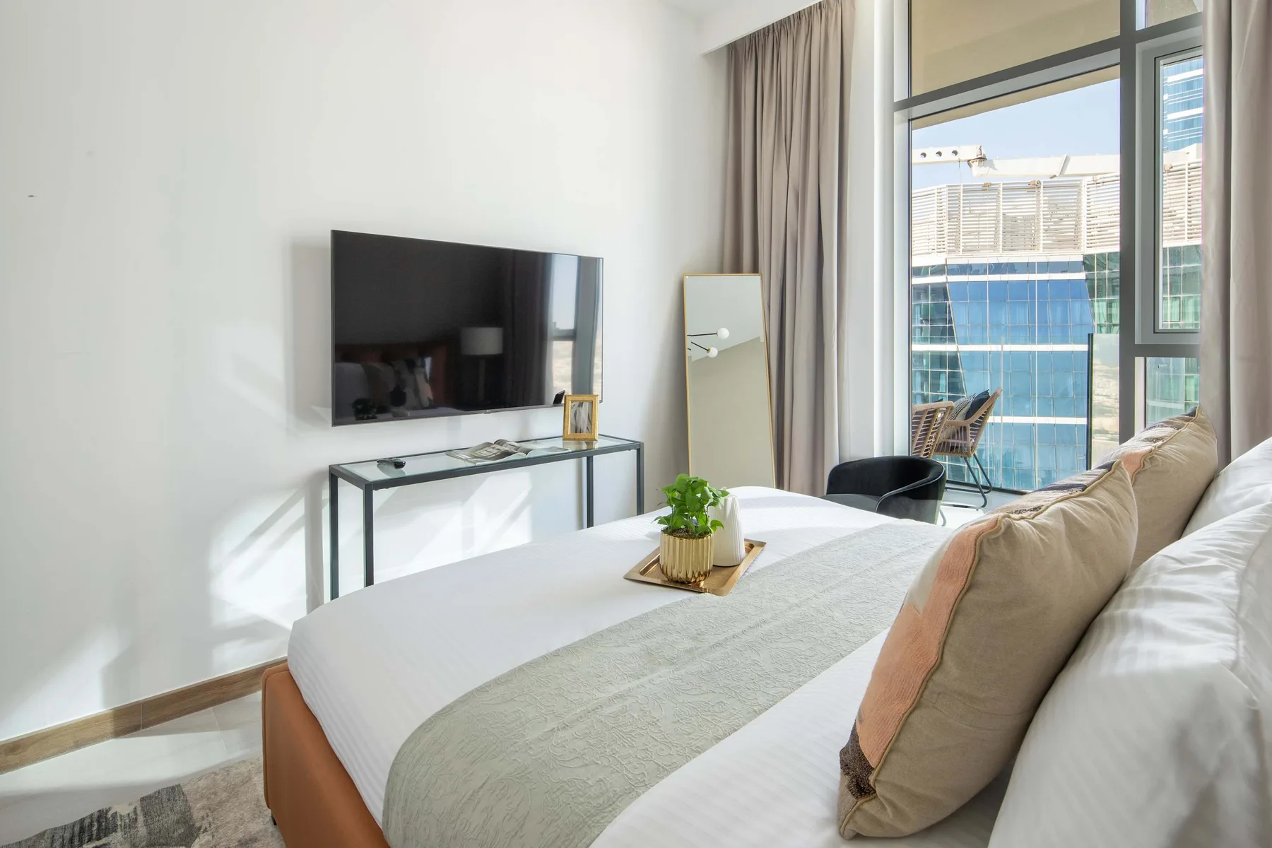 A bright bedroom with a neatly made bed and a large window.