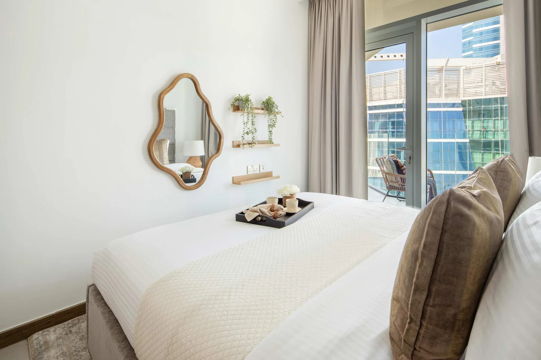 A bright bedroom with a neatly made bed beside a large window.