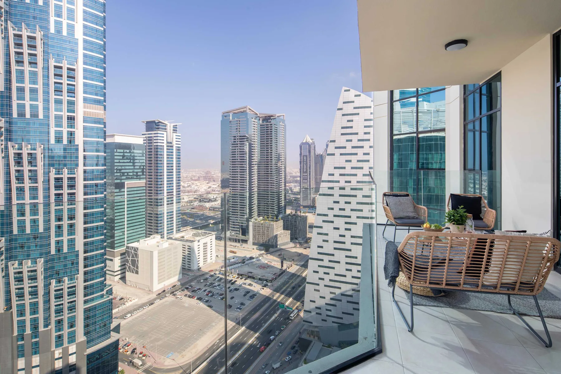 A balcony with seating overlooks a city skyline of high-rise buildings.