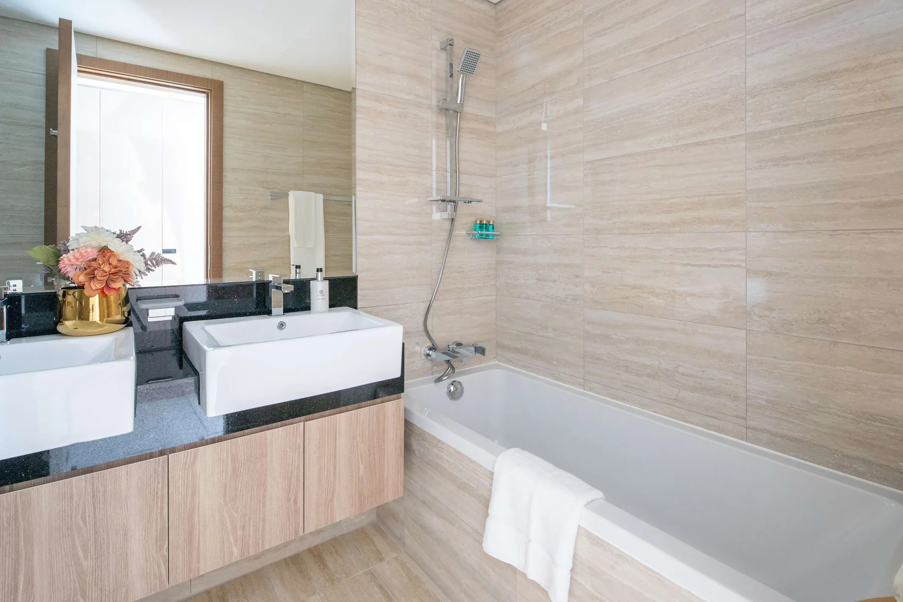 A bathroom with a bathtub and two sinks along the counter.