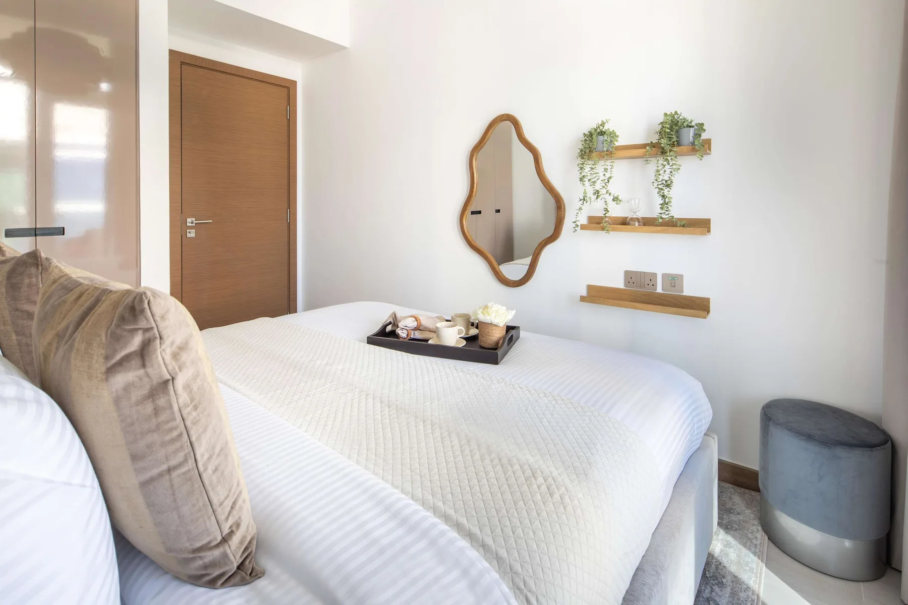 A bedroom with a neatly made bed and small wall shelves.