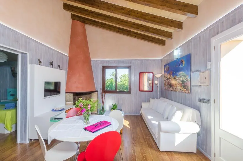 Una sala luminosa con asientos blancos, una mesa de comedor y un techo con vigas vistas.